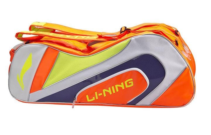 An orange and white sports bag, branded with "Li-Ning," made from durable polyester. This versatile Li-Ning National Team 6 Piece Racket Bag includes multiple zippers and compartments, along with a dedicated shoe section for convenient storage of your athletic gear.