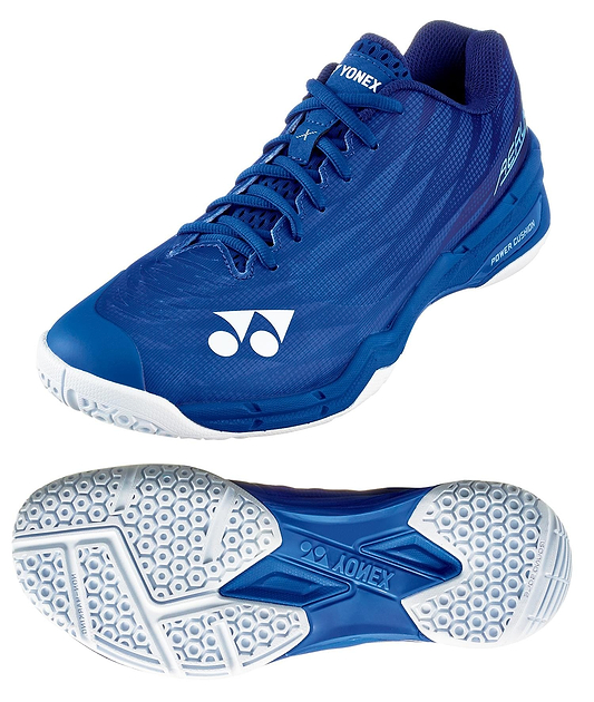 The Yonex Power Cushion Aerus X2 Unisex Badminton Shoes in navy blue are shown from the side and bottom, highlighting their white hexagonal-patterned sole with the Yonex logo, Power Cushion technology, white accents, and a lace-up design.