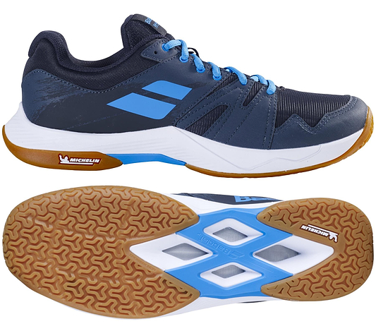 The Babolat Shadow Team 2 Men's Badminton Shoes in black and grey feature a gum sole with Michelin Rubber; side and bottom views showcase the tread pattern and color details.