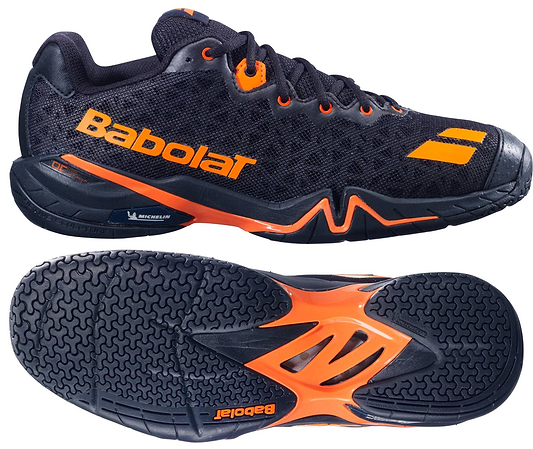 The Babolat Shadow 4 Men's Badminton Shoes in black and orange are shown from the side and sole views, featuring a mesh upper with "Babolat" branding and a textured rubber sole highlighted with orange accents.