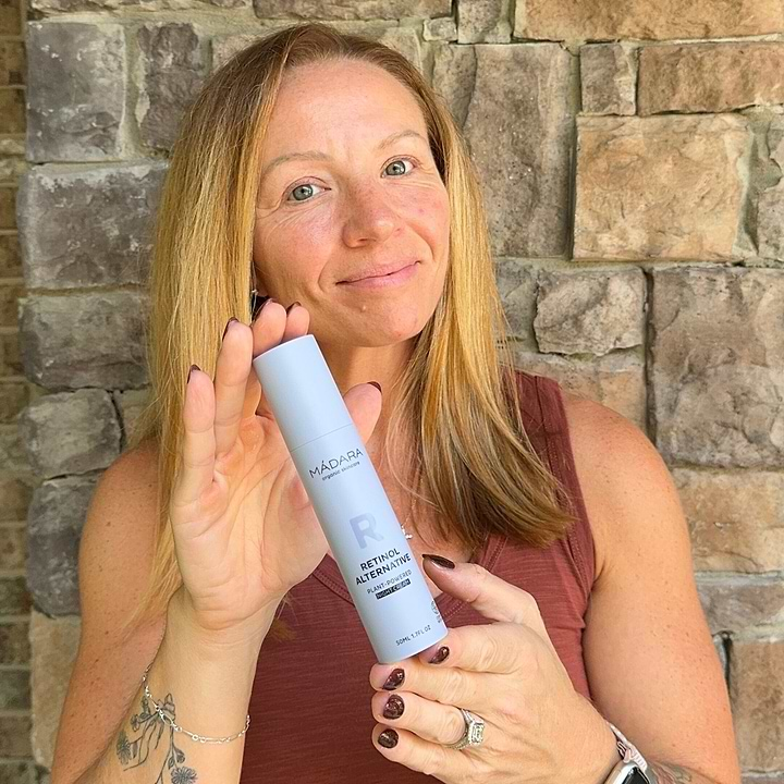 Woman holding a bottle of Mádara Retinol Alternative Night Cream for face highlighting the skincare product for natural anti-aging benefits