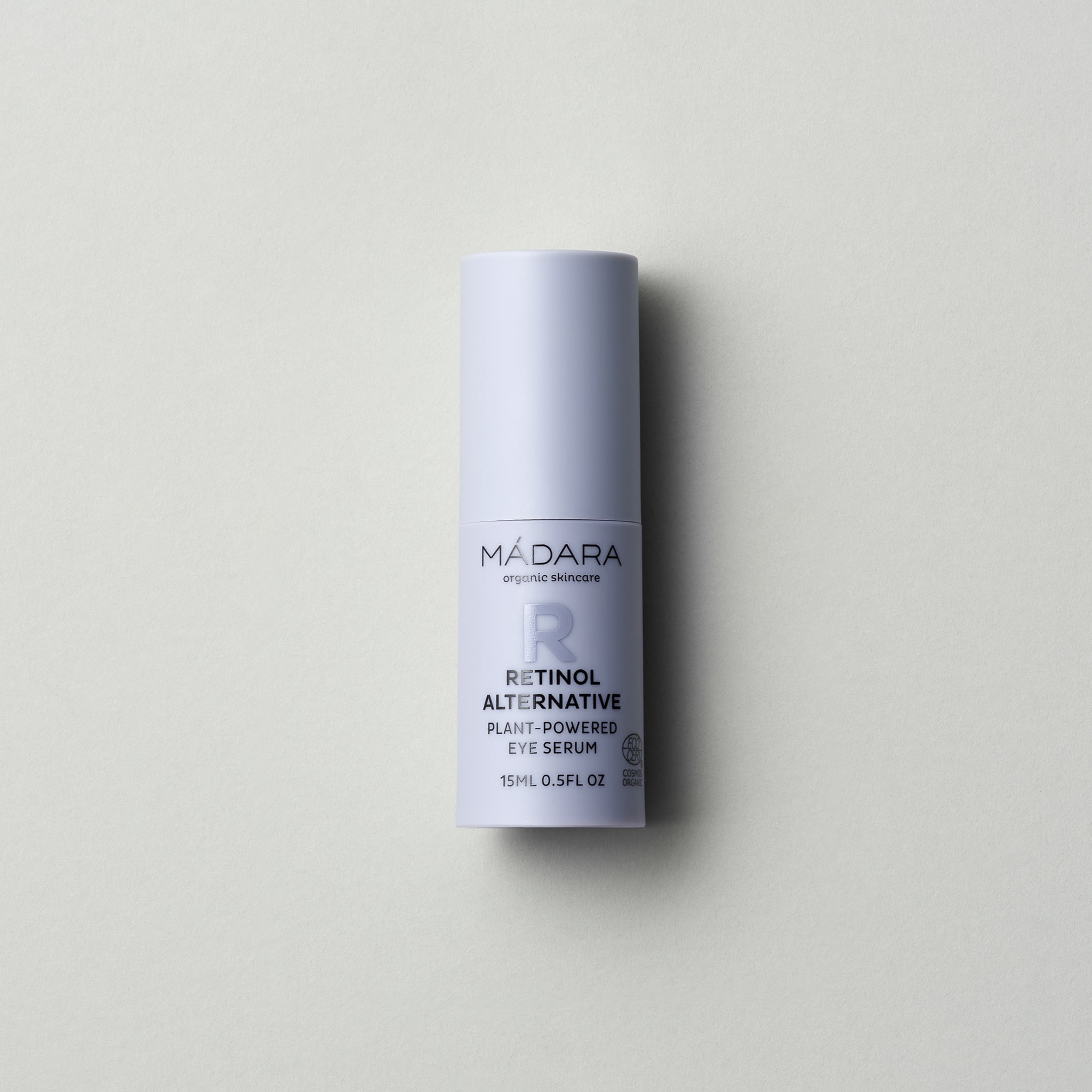 A 15 ml pump bottle of Madara Organic Skincare Retinol Alternative Plant-Powered Eye Serum with cap on a grey background