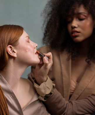 A Woman is Having Her Lips Painted with Lipstick by Another Woman Using Madara Organic Skincare