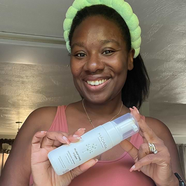 Woman holding a bottle of Mádara Cosmetics Purifying Foam for face cleansing