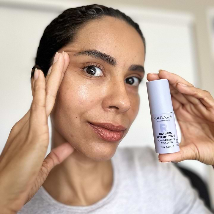 **Optimized version:**  
Woman holding a bottle of Mádara Retinol Alternative Eye Serum, emphasizing natural skincare for under-eye care and anti-aging benefits.