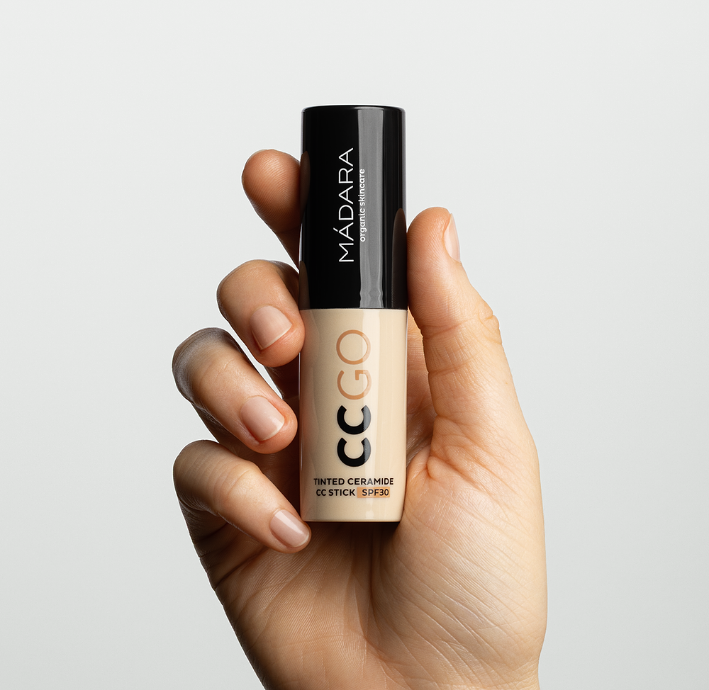 Hand holding MÁDARA CC GO Tinted Ceramide CC Stick SPF30, a portable complexion stick for lightweight coverage and sun protection