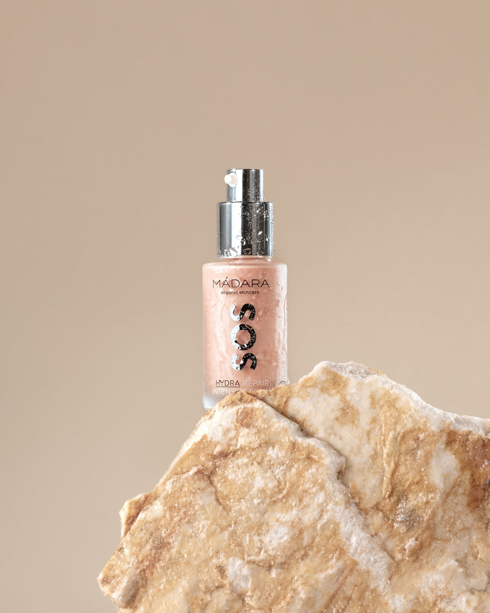 MÁDARA SOS Hydra Repair Serum bottle resting on a rock.