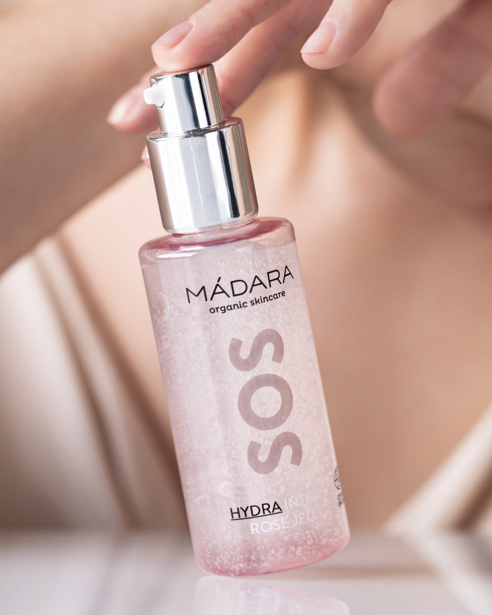 A hand gently holding MÁDARA SOS Hydra Intense Rose Jelly.