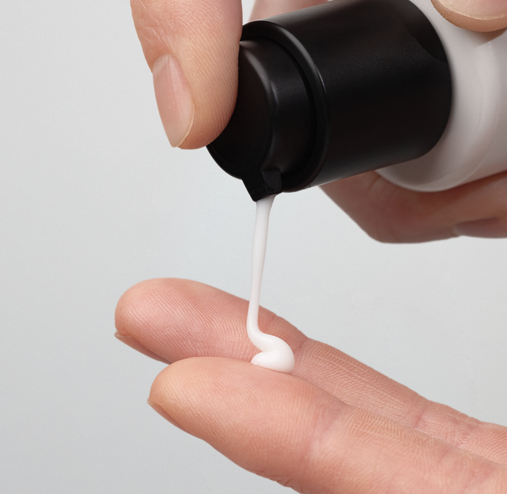 close-up of a hand dispensing madara HIS face cream from a black pump bottle onto fingertips