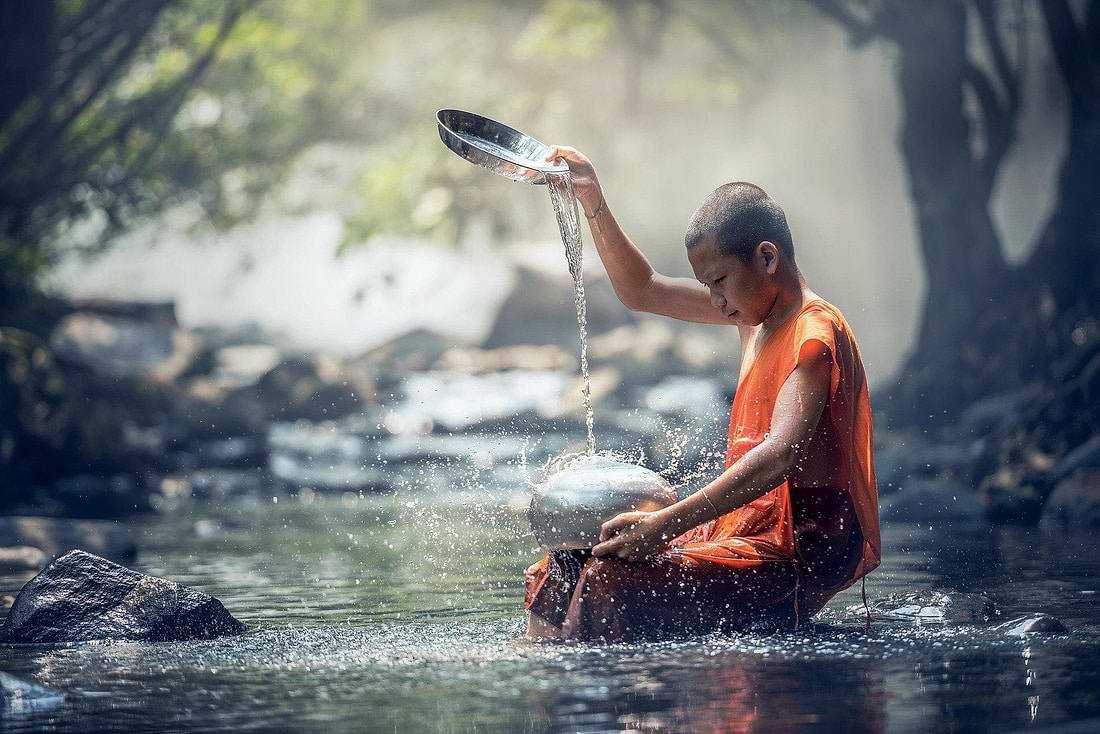 monk cleaning bowl at river