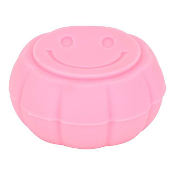 High angle and front shot of pink round silicone container smoking accessory with smiley design on lid
