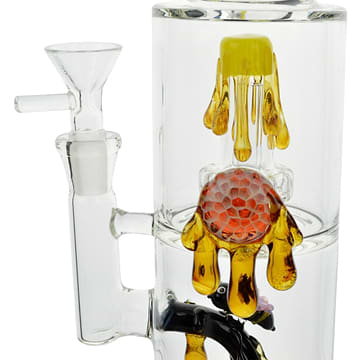 Close up shot of bong's ice restriction with dripping honey, honeycomb and honeybee design with bowl on the left