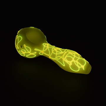 Full shot of 4-inch glass yellow pipe with illuminated glow in the dark swirls black background bowl on left