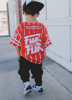 Child wearing a Mini Speedsters Jersey red and white walking on a sidewalk.