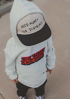 Child wearing a hoodie and Little Trouble Need $ For Dirt Bikes Snapback Tan on a neutral background