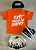 Orange t-shirt with 'Fast Makes Me Happy' text, black cap, white shorts with black flame design, and black and white sneakers on a gray surface.