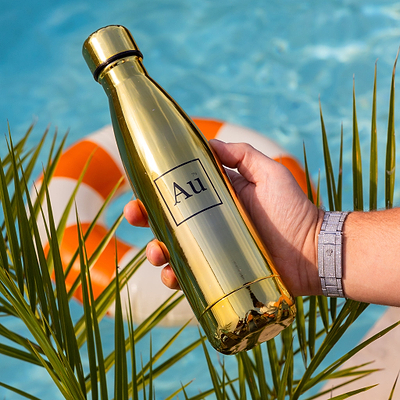 Hand holding a gold Au Vodka USA water bottle over a swimming pool with a life preserver