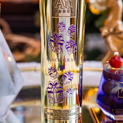 Au Vodka Black Grape Bottle, with a Christmas Present Design Printed on the bottle, over a blurred background.