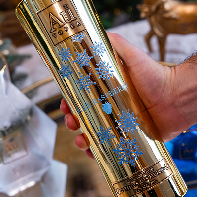 Au Vodka Blue Raspberry Christmas bottle held in hand against  a blurry background