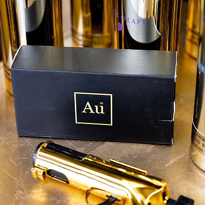 Gold toy gun and black box with 'Au' logo on a marble surface
