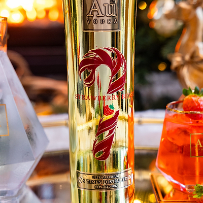 Gold bottle of Au Vodka Strawberry Burst with a blurred background