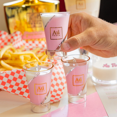 Au Vodka Strawberry Milkshake in a Shot Glass on a diners table with dessert items