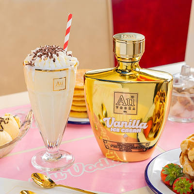 Au Vodka Vanilla Ice Cream labeled next to a Sundae Glass with whipped cream and a red straw on a pink tablecloth.