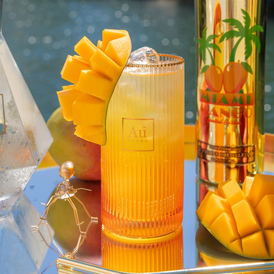 Au Vodka USA mango cocktail with sliced mango garnish and Au Vodka bottle