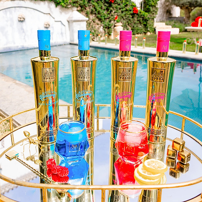 Gold bottles with colorful caps on a reflective surface near a pool
