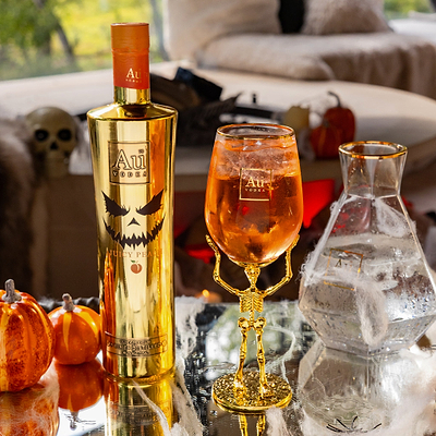 Au Vodka bottle and Skeleton glass with Halloween-themed decor in the background