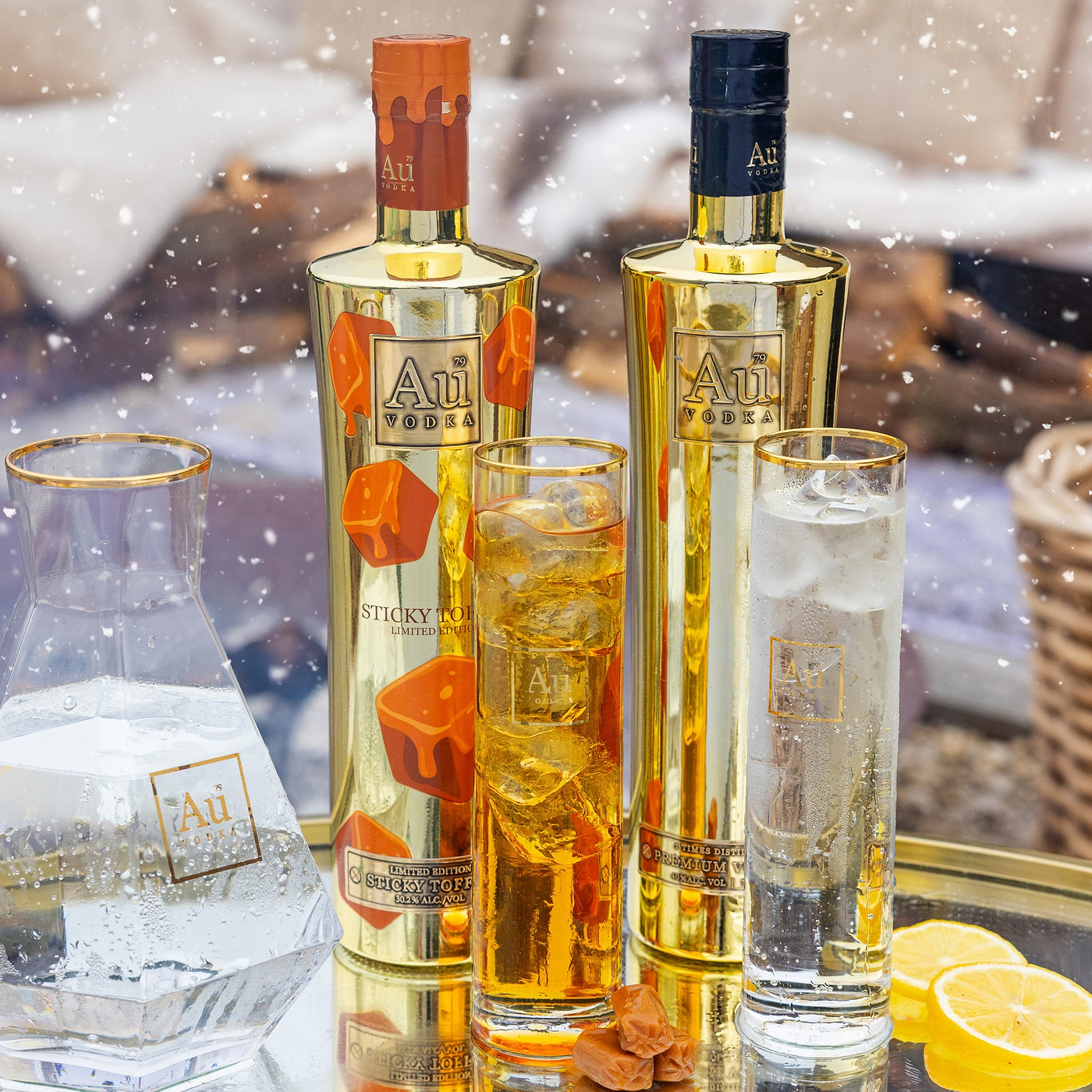 Two bottles of Au Vodka with glasses filled with the drink, set against a blurred outdoor background.