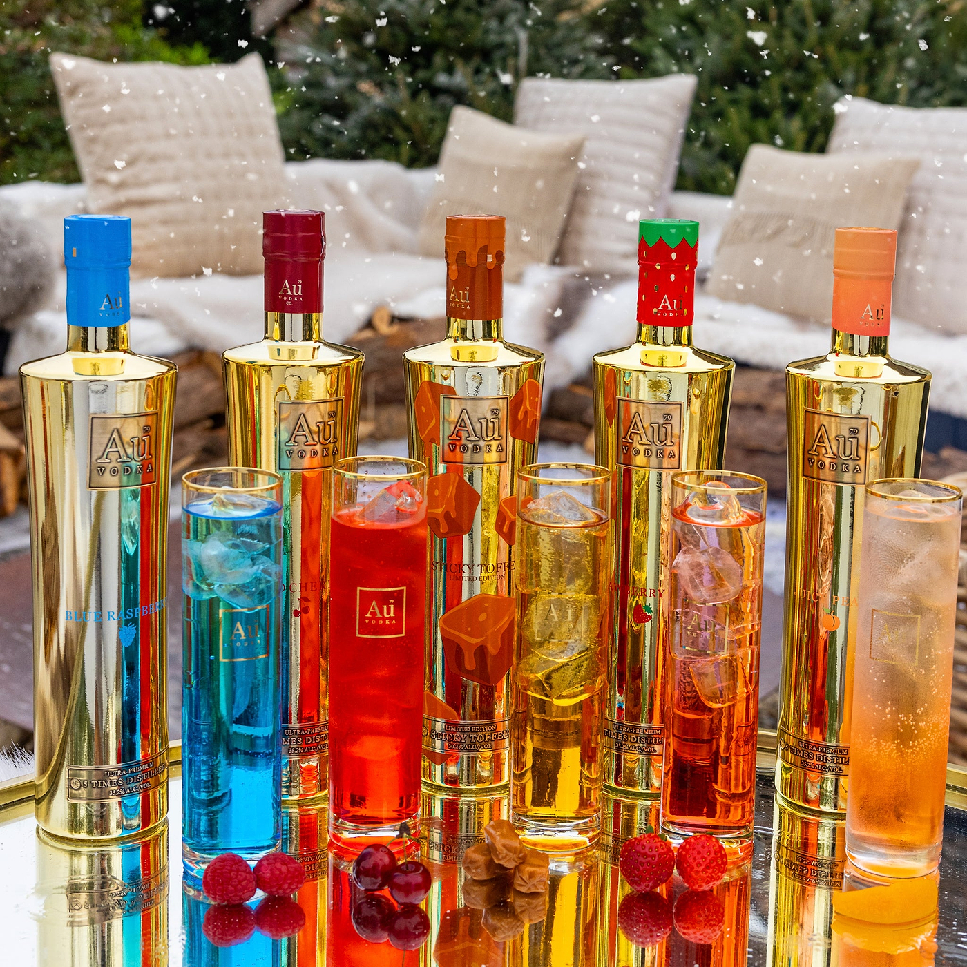 Colorful bottles and glasses with 'Au' branding on a reflective surface.