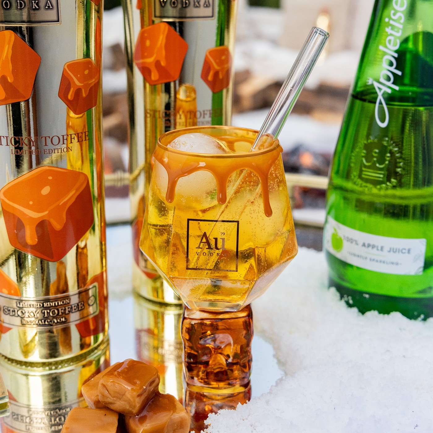 Alcohol bottles with a cocktail in the foreground on a reflective surface
