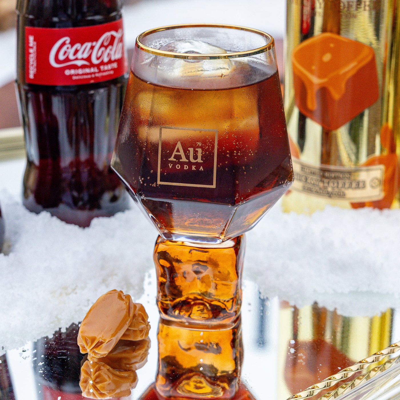Glass of Au Vodka with Coca-Cola and a bottle of Au Vodka on a snowy background