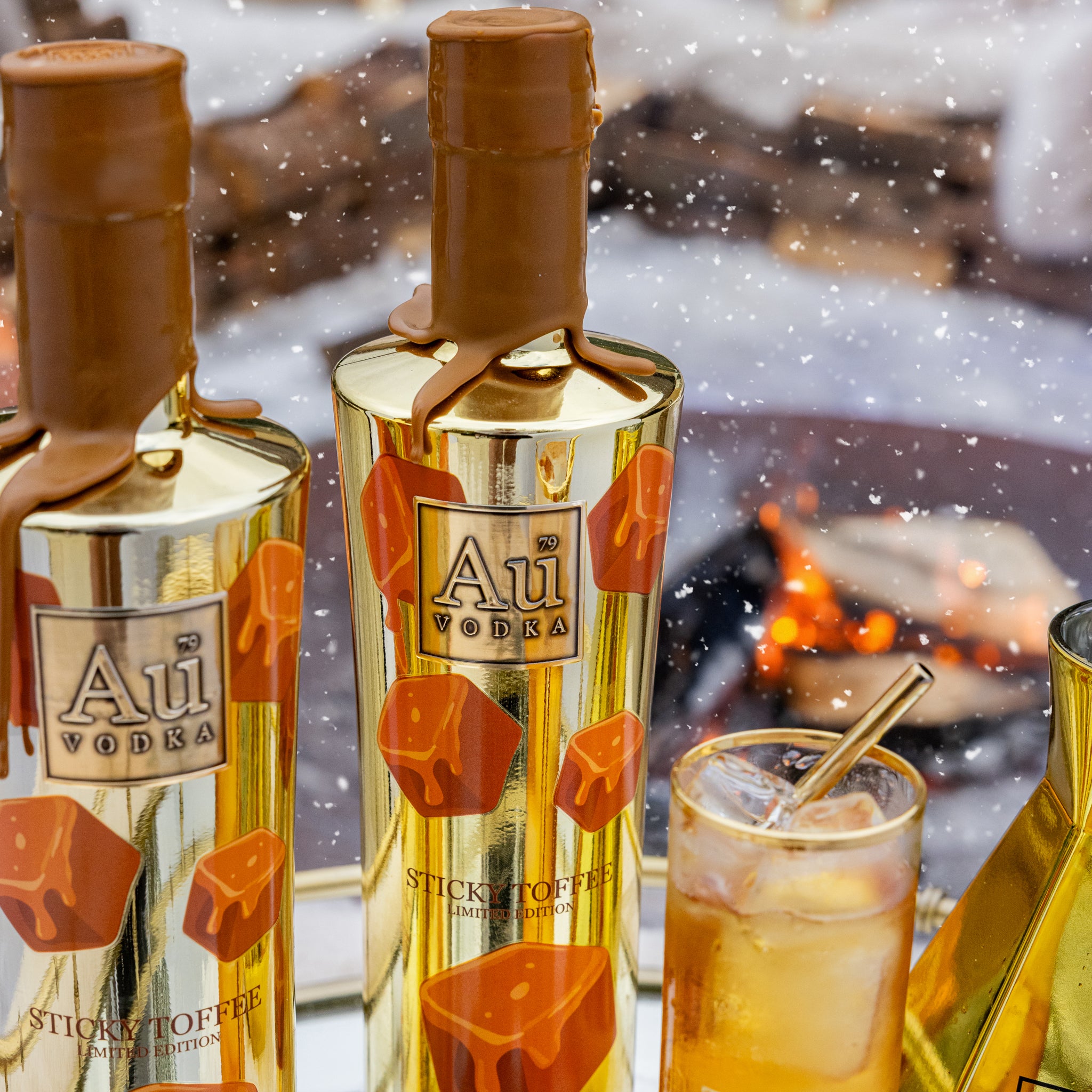 Two bottles of Au Vodka with a snowy background and a highrise glass