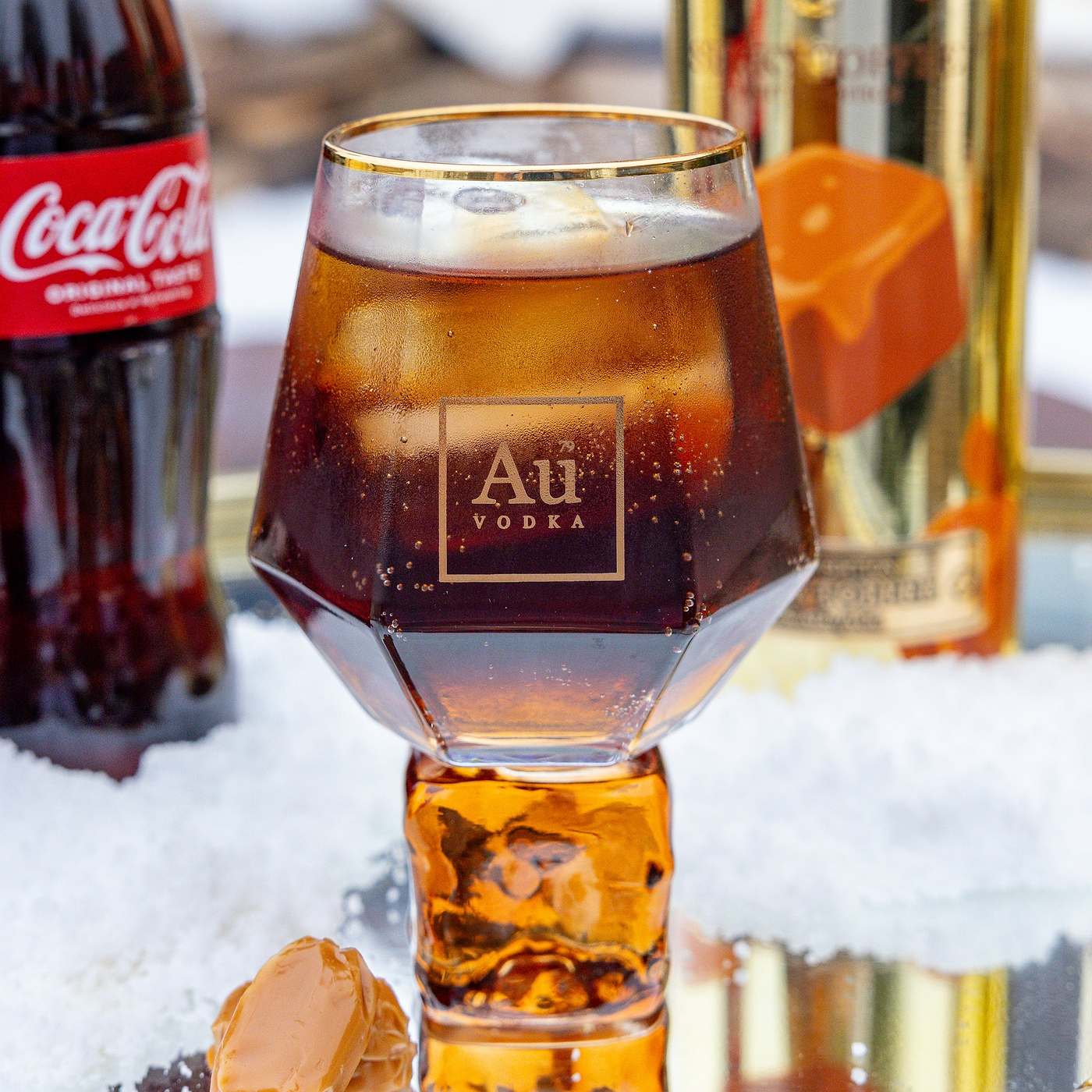 Glass of Au Vodka cocktail with Coca-Cola bottle and other drinks in the background