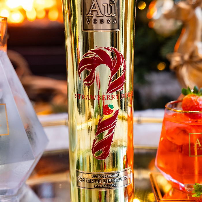 Gold bottle of Au Vodka Strawberry Burst with a blurred background