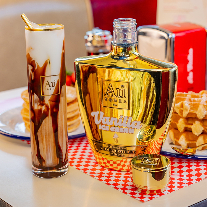 Au Vodka labeled 'Au Vanilla Ice Cream' with a Au Highrise Glass with chocolate sauce on a checkered tablecloth.