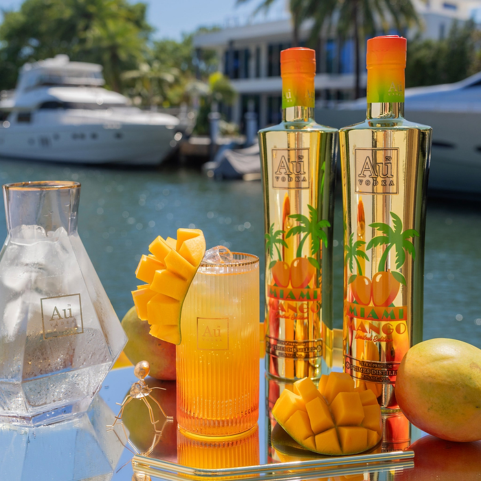 Au Vodka USA Mango Passion bottle and drink on a tray with mangoes by a canal