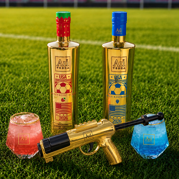 Two gold bottles of Au Vodka, a golden toy gun, and two glasses filled with a red and blue liquid on grass.