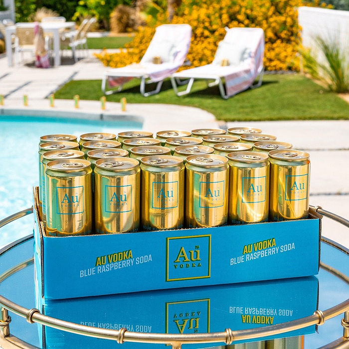 A case of Au Vodka Blue Raspberry Soda cans on a tray by a pool