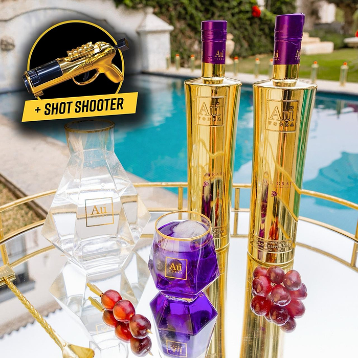 Au Vodka USA Black Grape vodka bottles, decanter, glass, grapes, and shot shooter on a mirrored tray