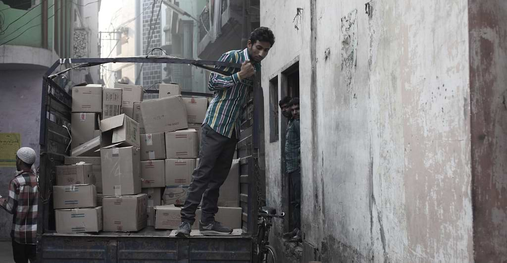 Indian man on the back of a loaded vehicle