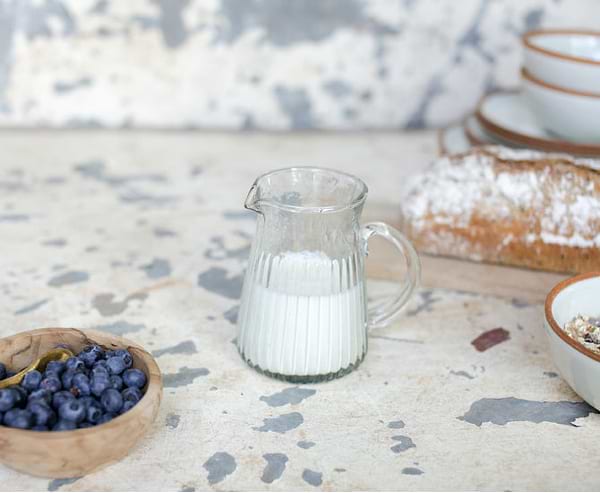 Bread, jug of milk and bowl of blueberries