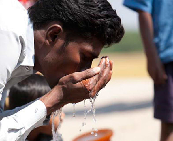 Man drinking water from his hands
