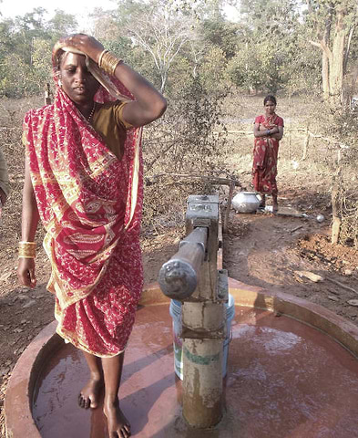 Two indian women taking water from a well