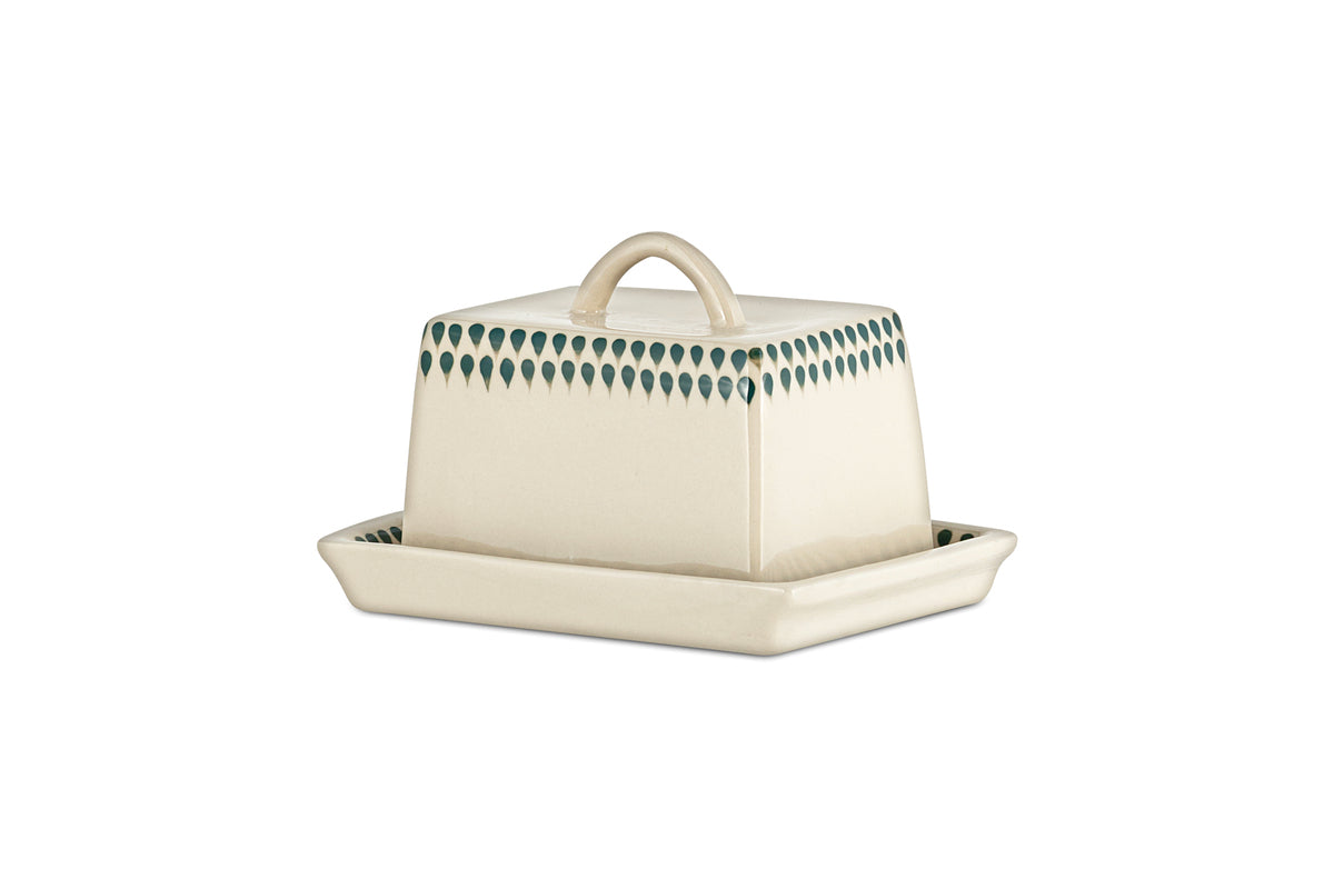 The nkuku Juniper Drop Butter Dish - Cream & Juniper features a rectangular ceramic design with a cream lid edged in green drops and a curved handle, offering both charm and elegance to your table.
