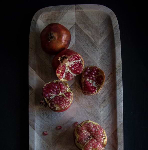 Fresh pomegranates on a wooden platter