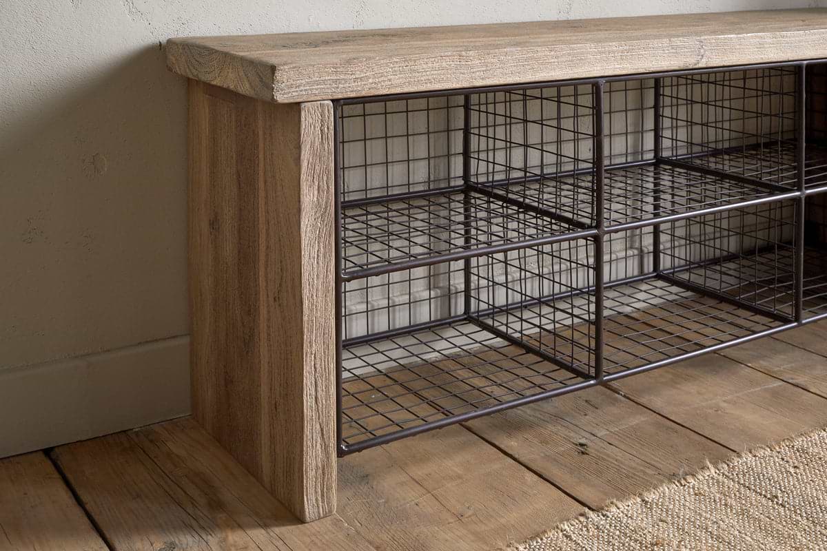 The nkuku Abha Reclaimed Wood & Iron Storage Bench - Natural features six open wire mesh cubbies, making it a perfect entryway organizer for your hallway. It sits stylishly on a wooden floor by a beige wall and woven rug.