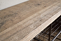 Close-up of the Abha Reclaimed Wood & Iron Storage Bench - Natural by nkuku, showcasing a textured wood tabletop with natural grain and knots, set above sturdy metal wire shelves—perfect as an entryway organizer or shoe storage bench.